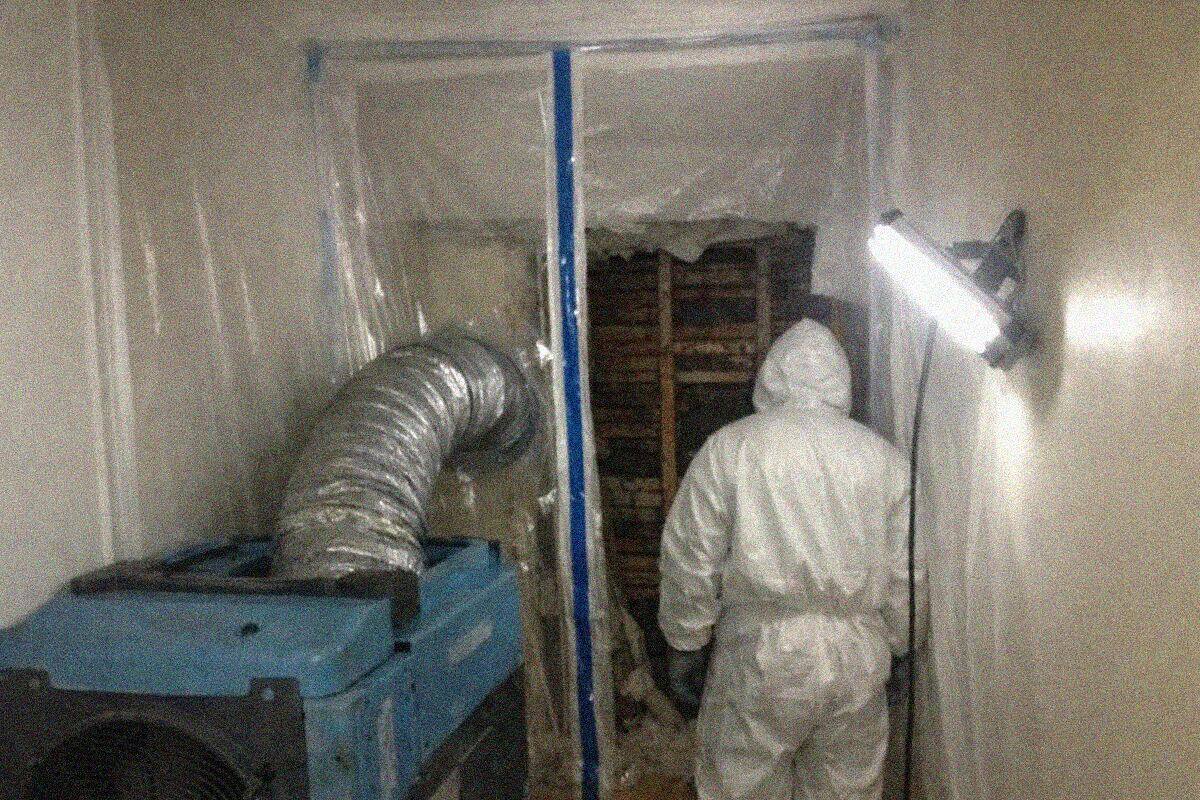 Plastic containment sheeting and a HEPA air scrubber set up in a New York apartment room during mold remediation